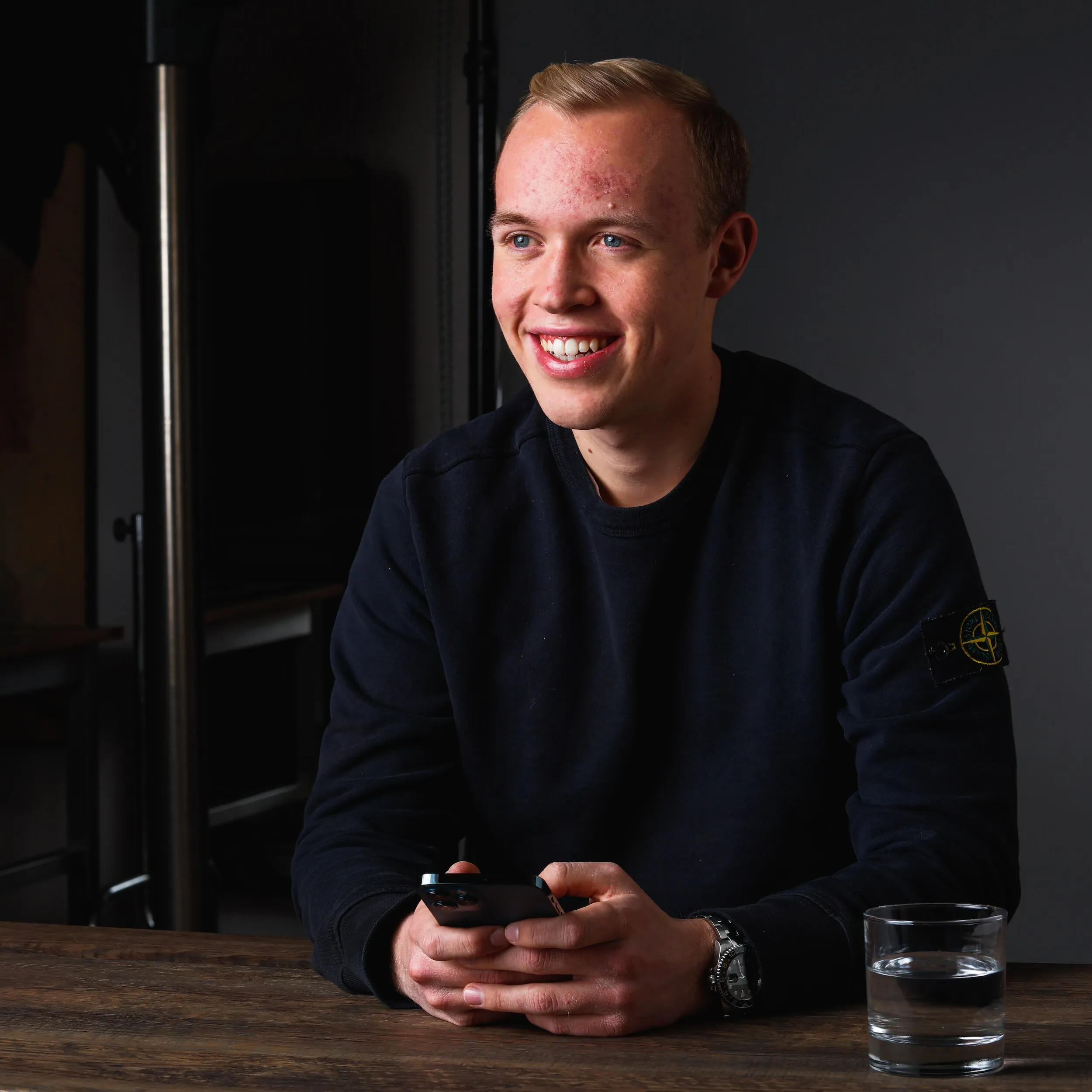 Maximilian am Brunnen smiling at a table, phone in hand