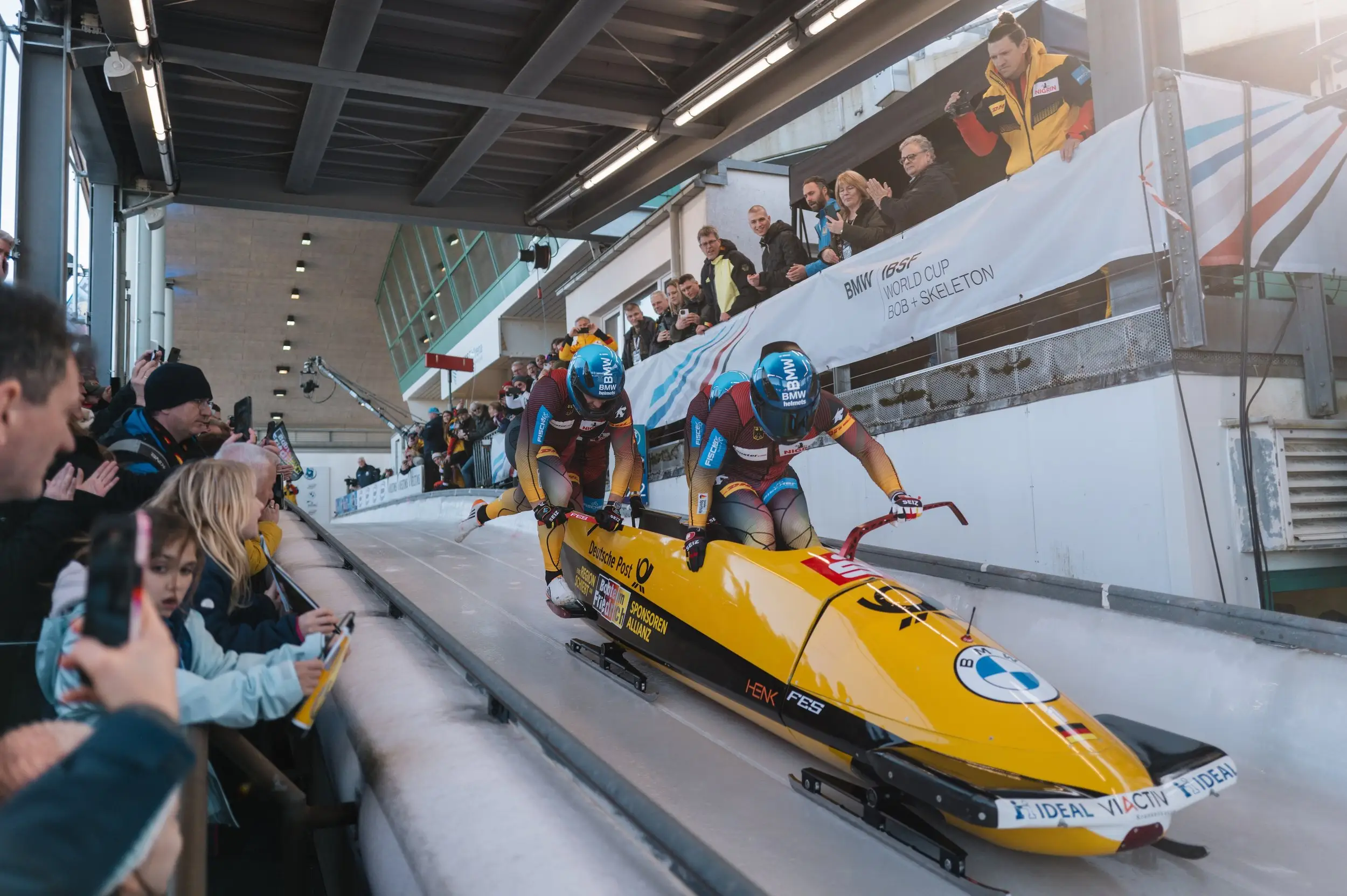 A yellow two-man bobsled leaving the start house in Winterberg